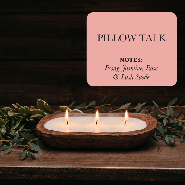 Three candles in a wooden holder with greenery on a dark background, featuring a 'Pillow Talk' product card.