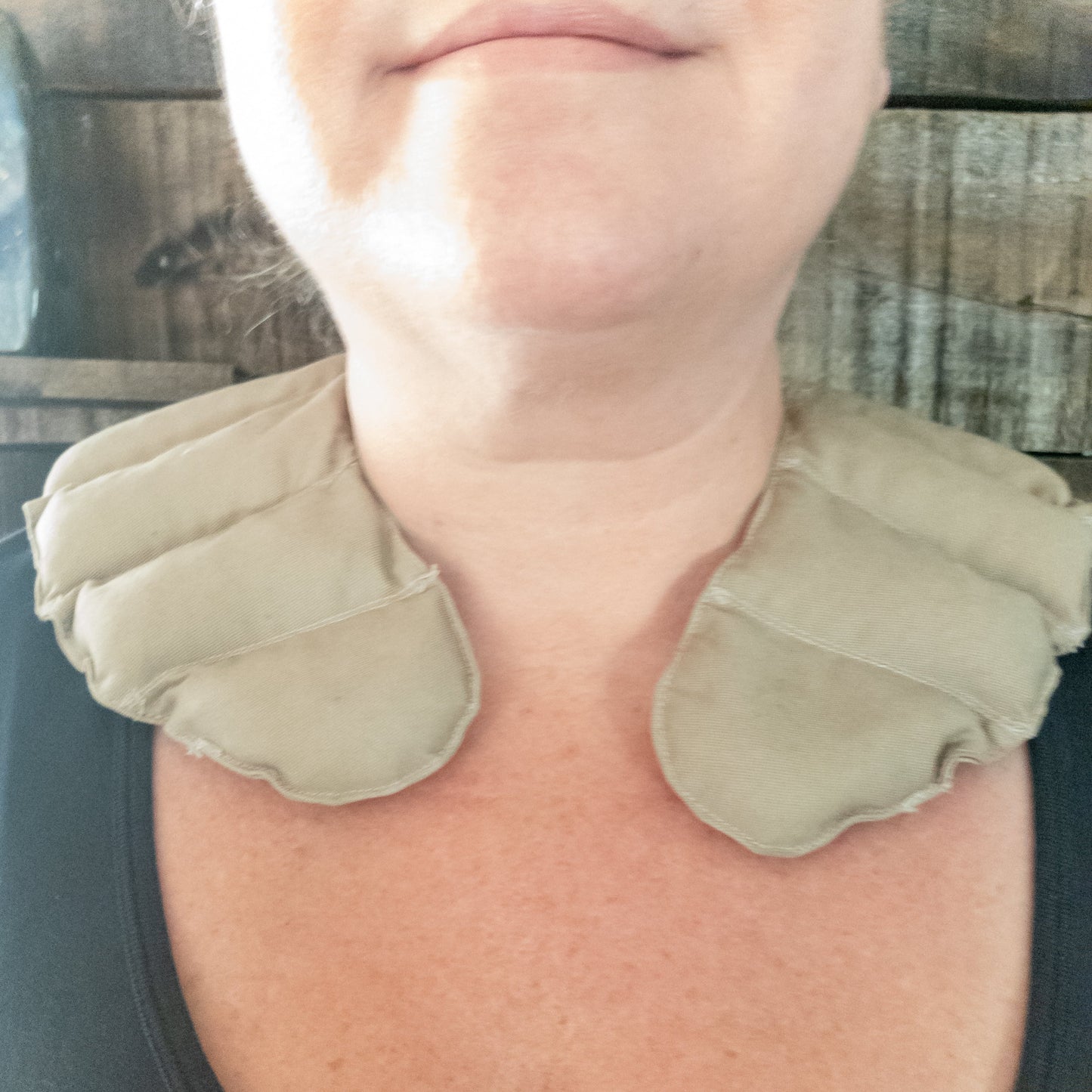 Person wearing a beige neck pillow with amethyst against a wooden background