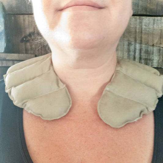 Person wearing a beige neck pillow with amethyst against a wooden background