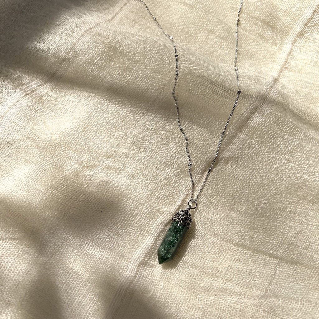 Necklace with a green aventurine pendant on a light fabric background