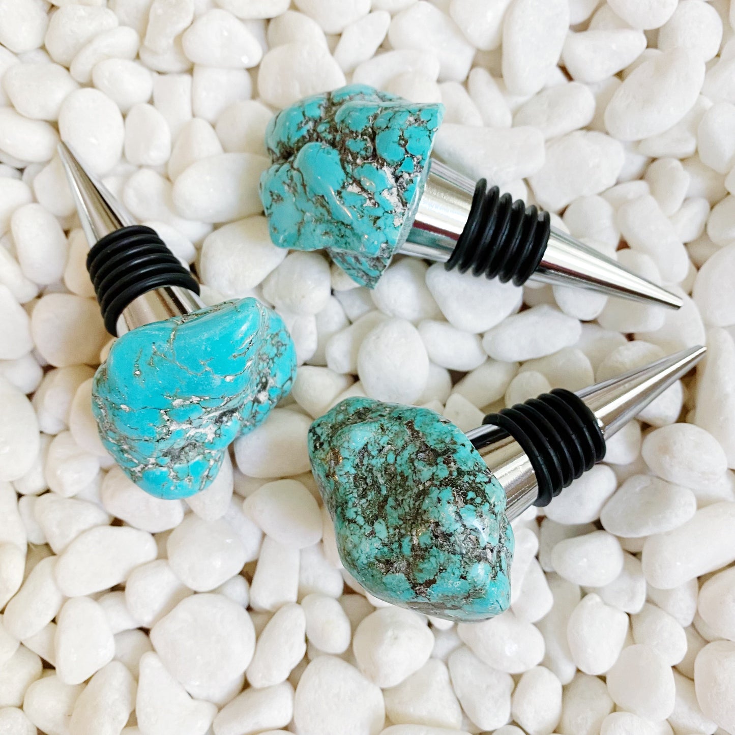Turquoise stone bottle stoppers on white pebbles
