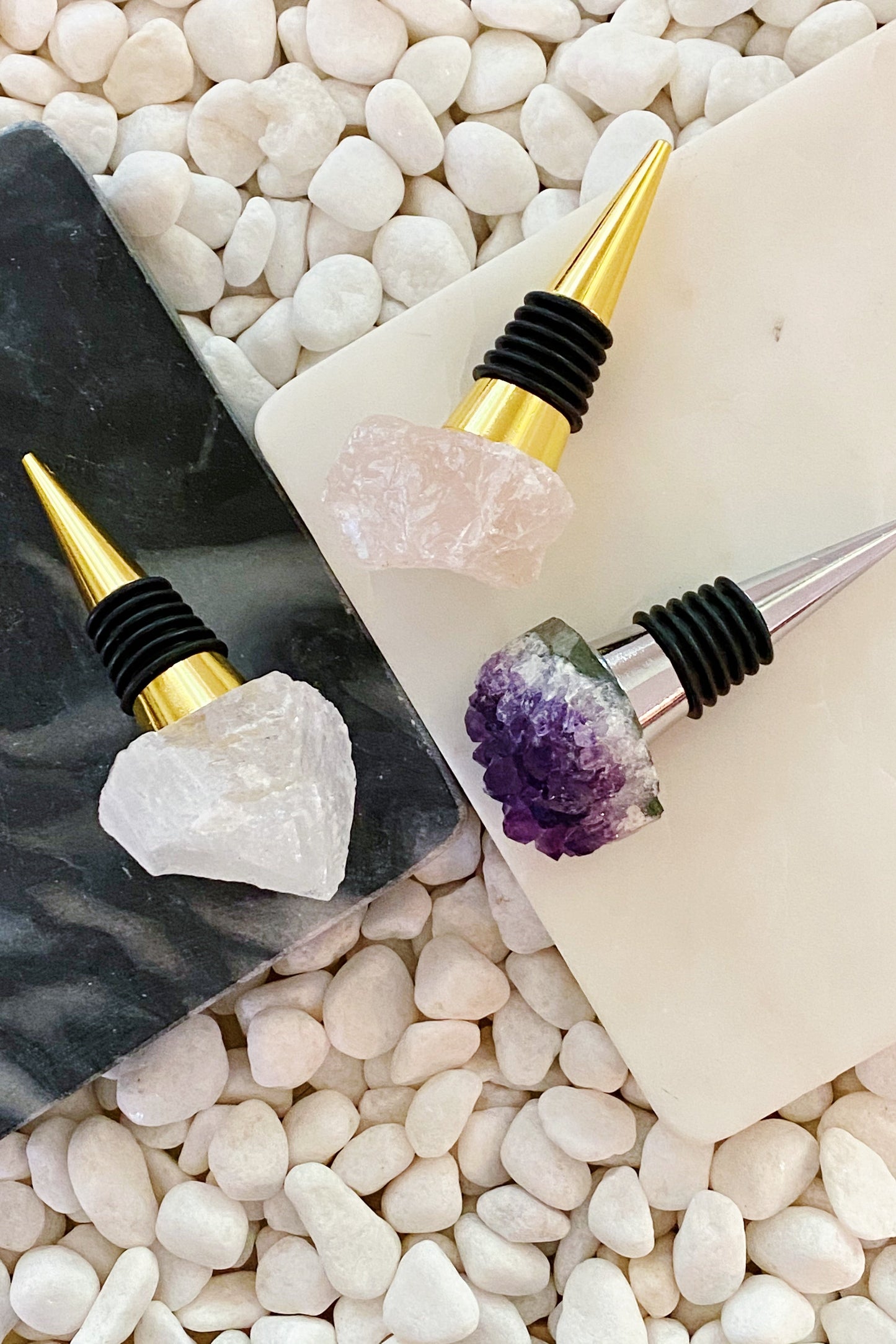 Wine bottle stoppers with natural stone and crystal designs on a pebble background