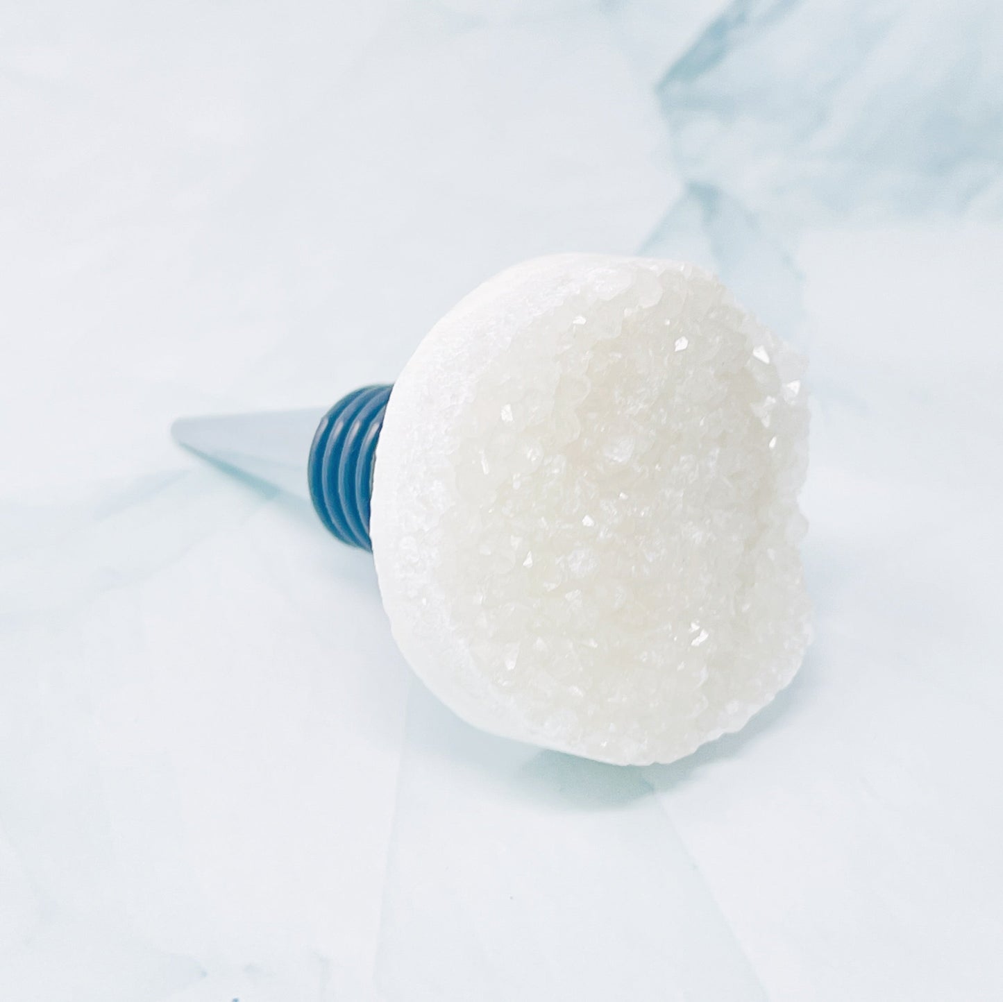 Close-up of a white crystal wine bottle stopper on a light blue background