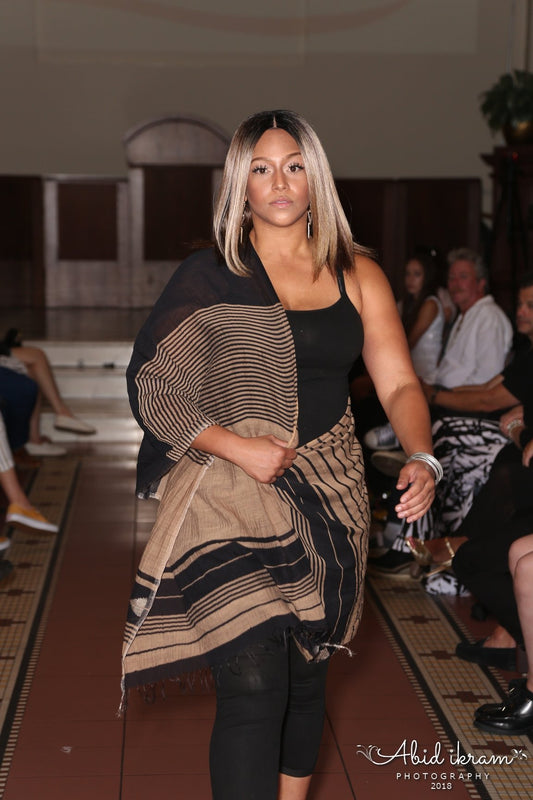 Model walking on a catwalk wearing a black and gold design silk shawl.