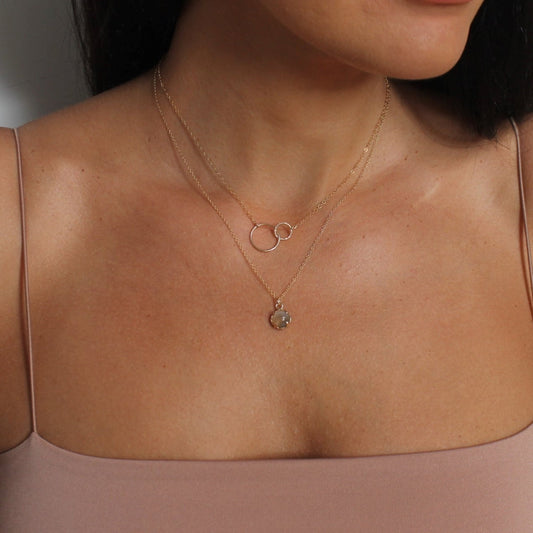 Close-up of a person wearing a delicate gold necklace with an agate pendant.