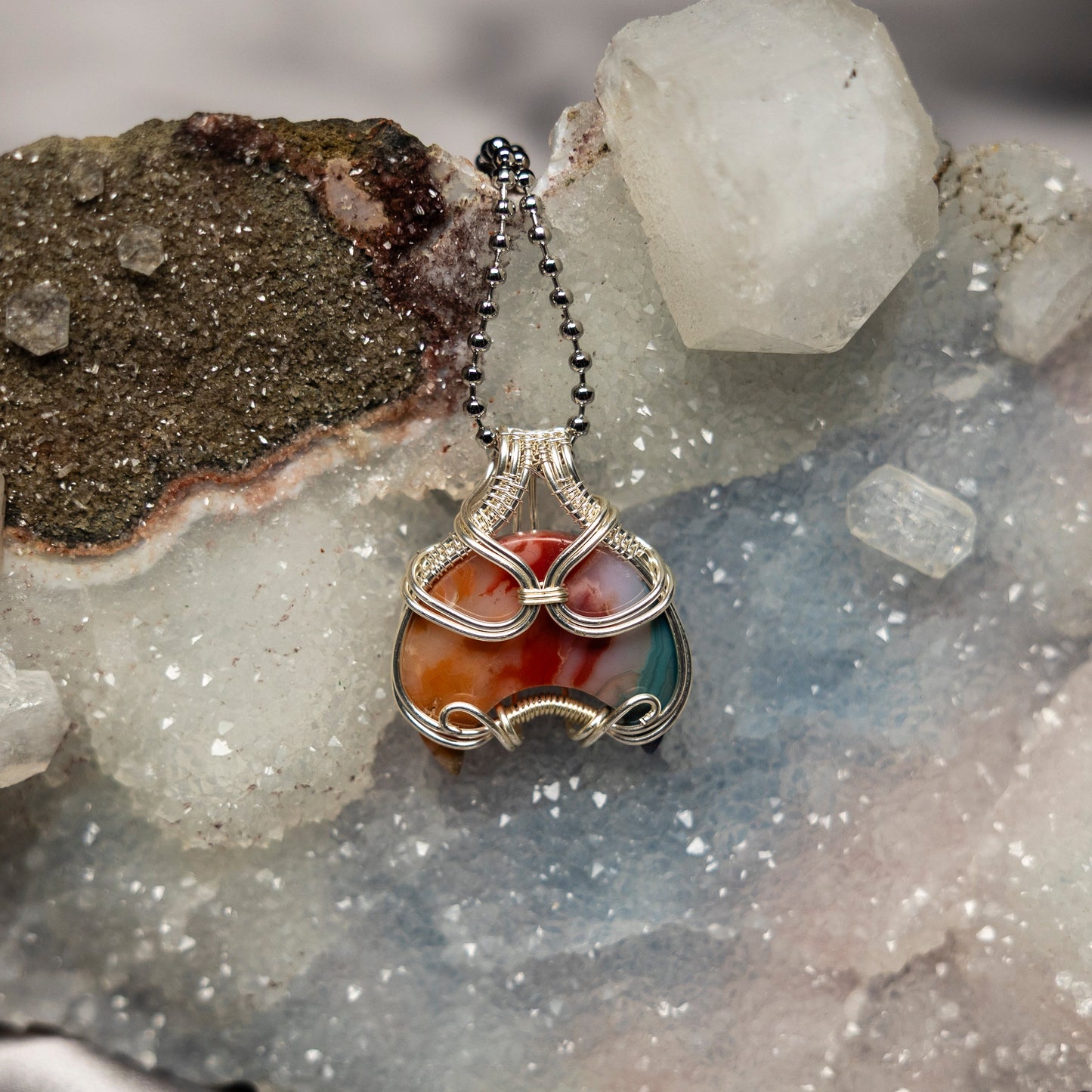 Necklace with a colorful chakra agate pendant on a crystal background