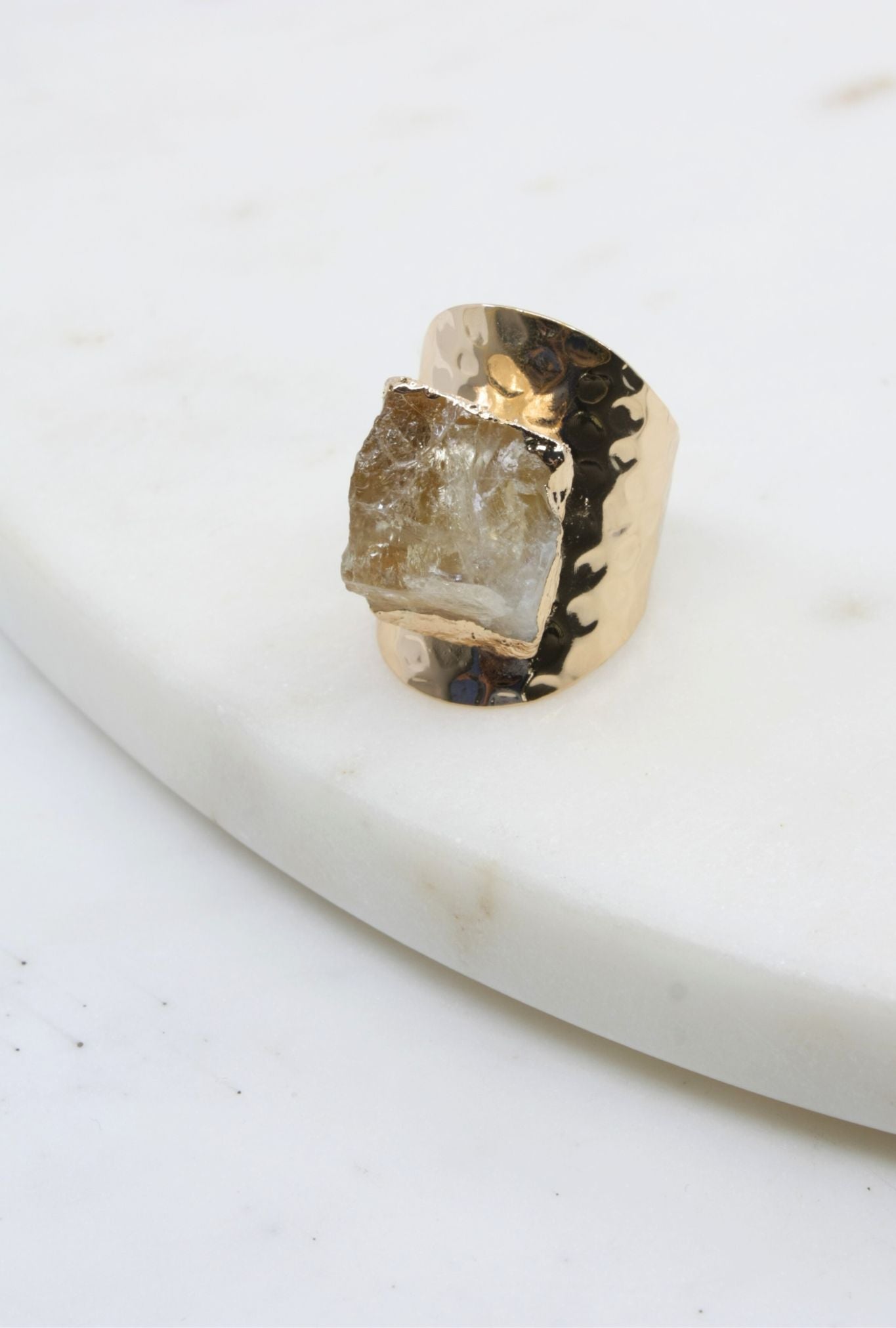 Gold ring with a rough-cut gemstone on a white surface