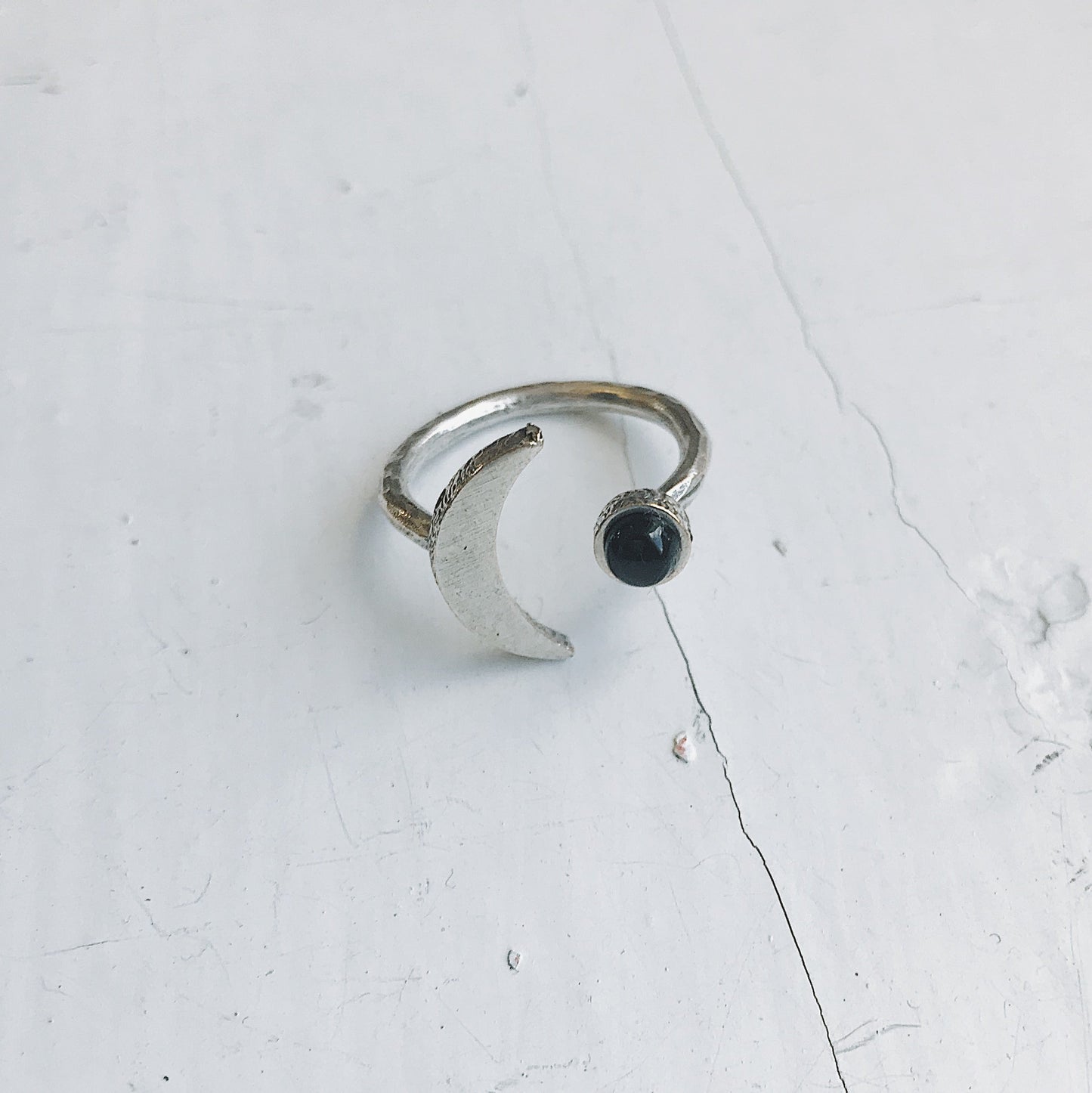 Silver ring with a black onyx gemstone on a light gray background