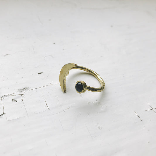 Gold ring with a black onyx gemstone on a white surface