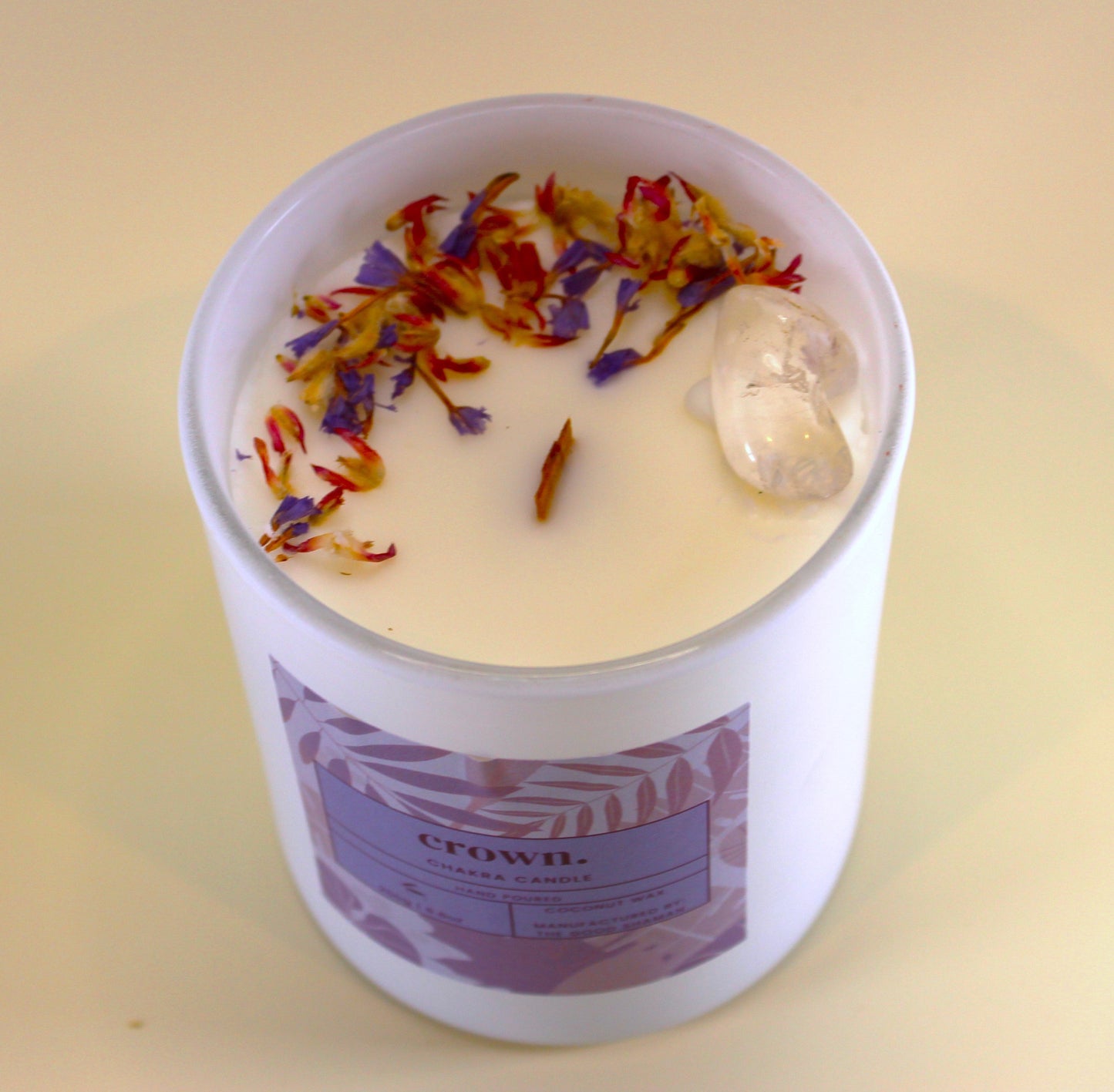 Candle in a white container with colorful dried flowers on top, labeled 'Crown'.
