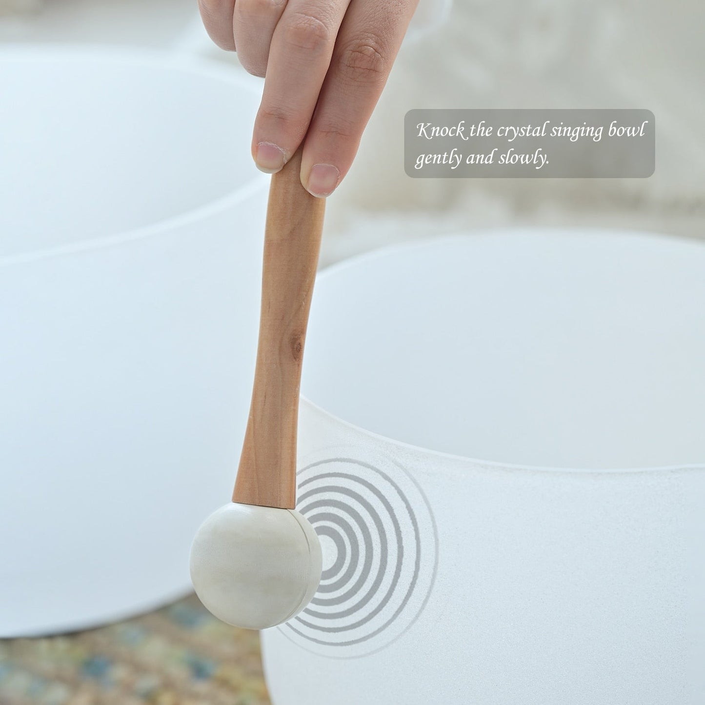 Crystal singing bowl with a wooden mallet and text instruction on a blurred background