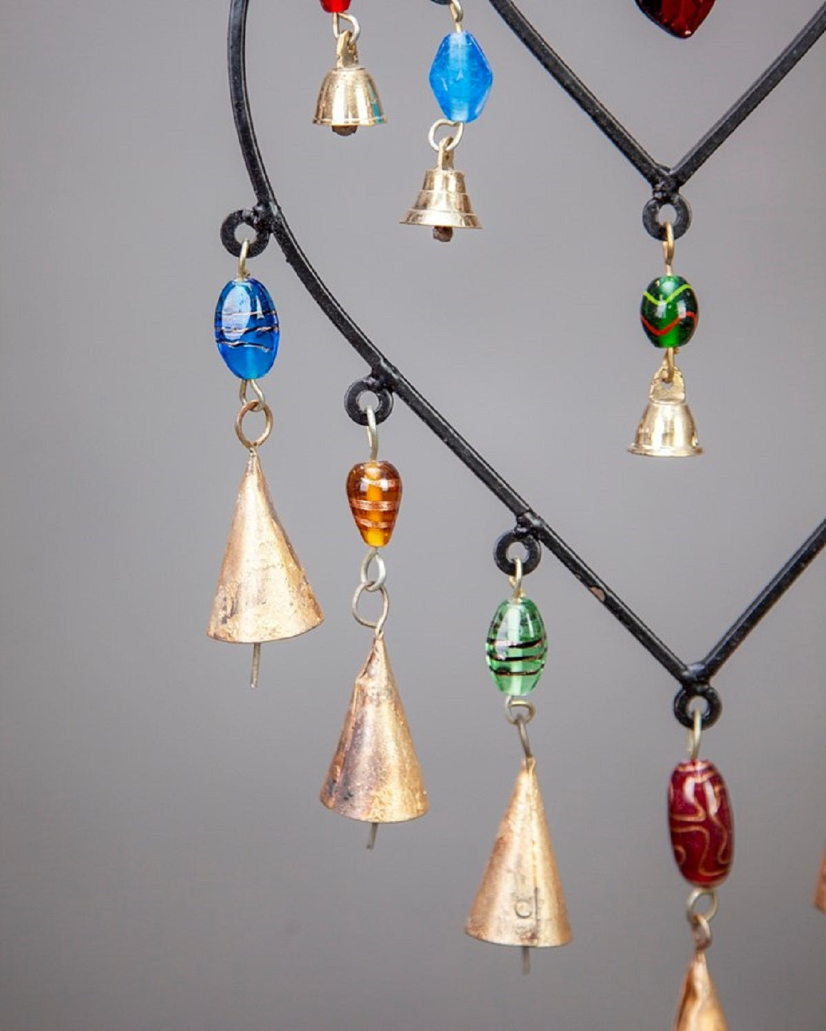 Decorative hanging with colorful beads and bells on a gray background