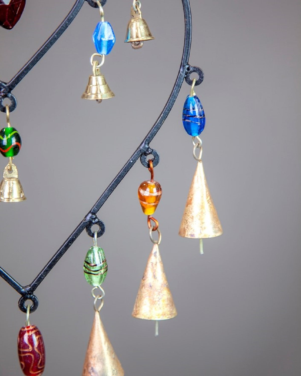 Decorative hanging chime with colorful beads and bells on a gray background