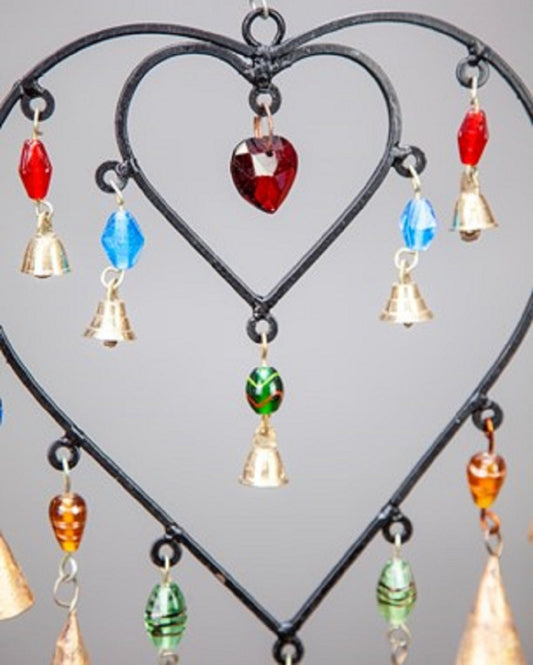 Decorative hanging heart with colorful beads and bells on a gray background