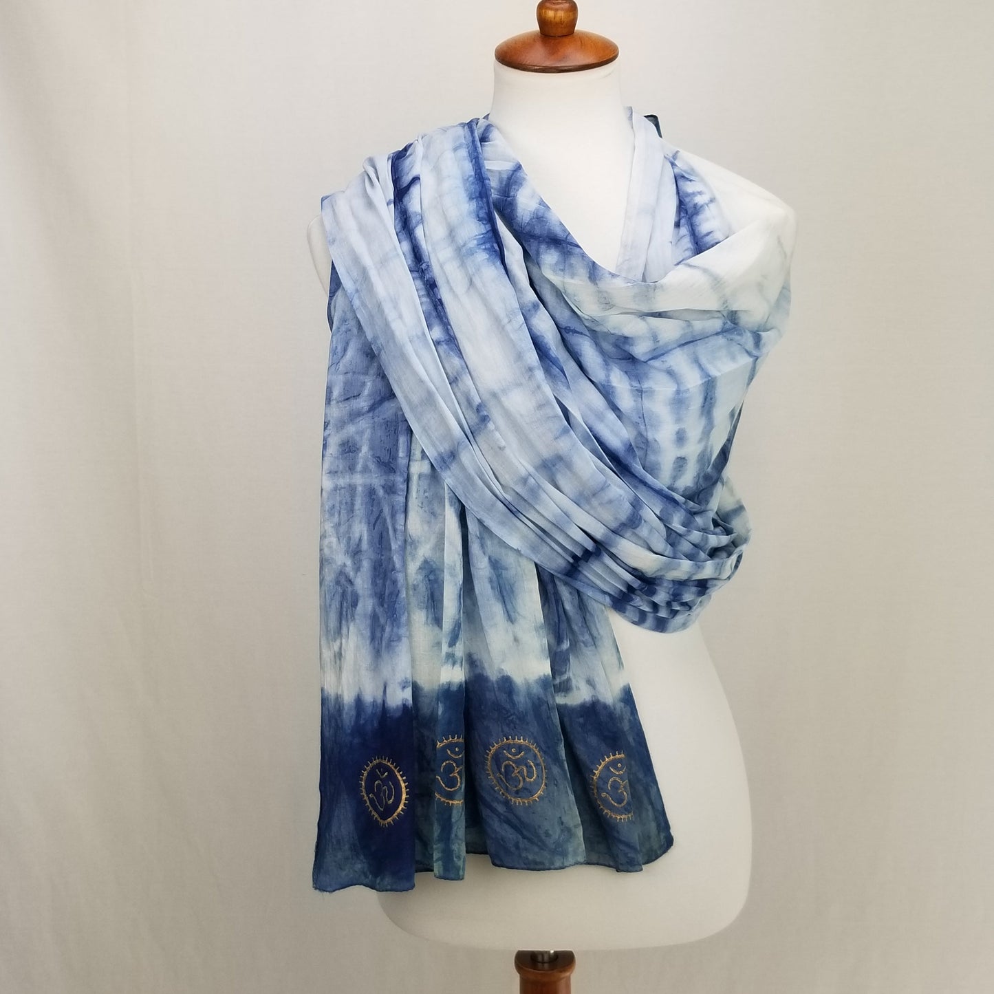 Blue tie-dye scarf with embroidered designs on a mannequin against a white background