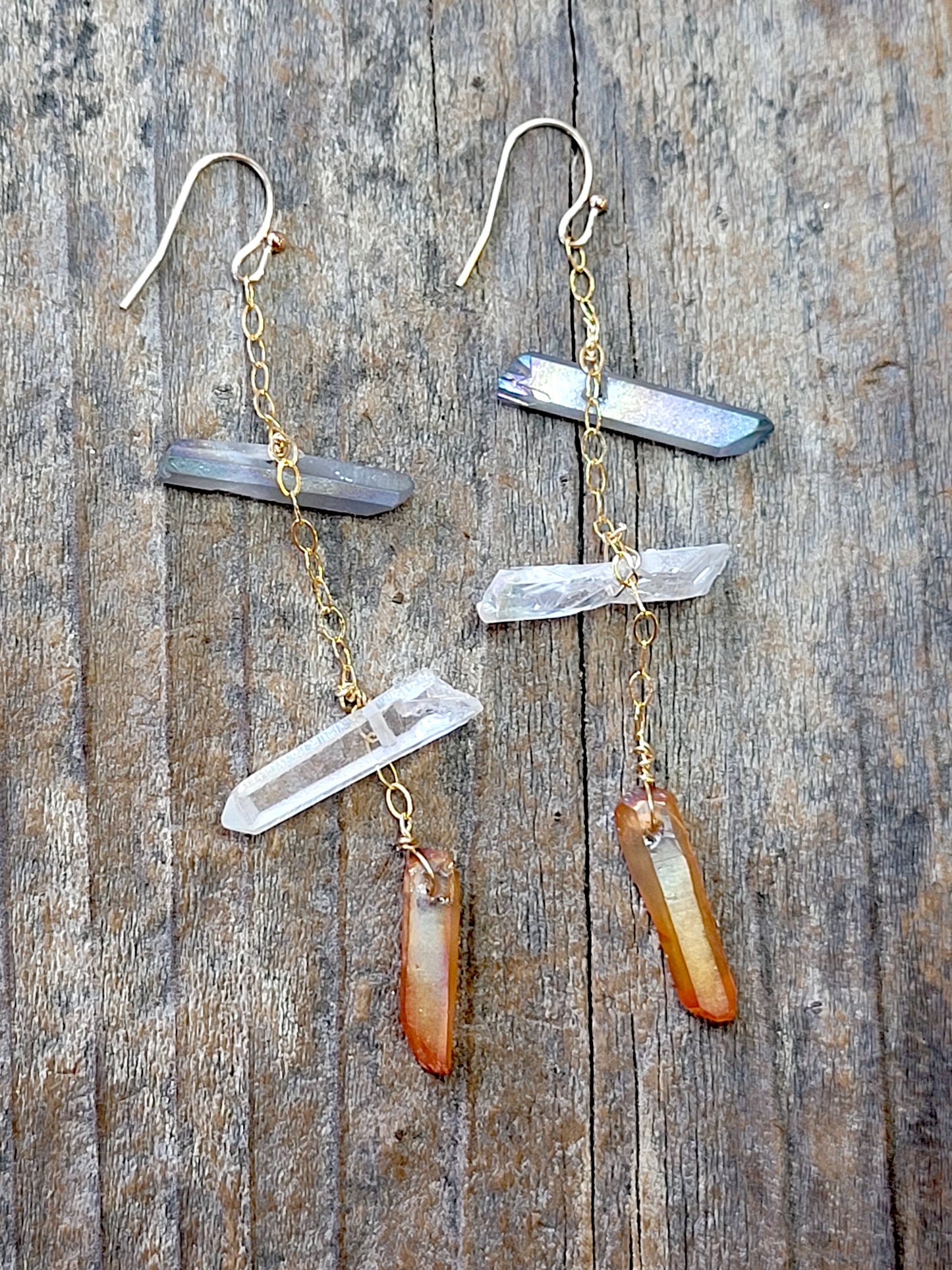 Pair of gold tone quartz crystal earrings on a wooden surface
