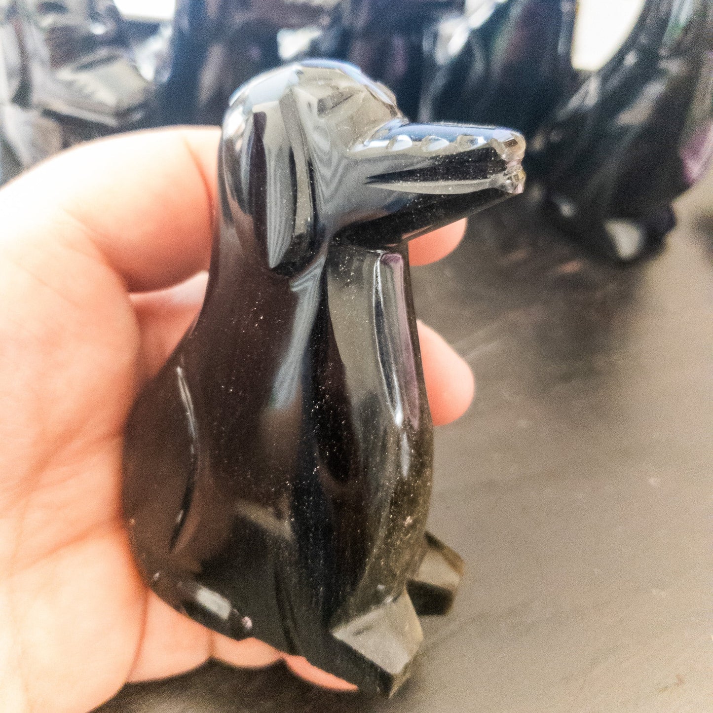 Hand holding a shiny black dog figurine with blurred background