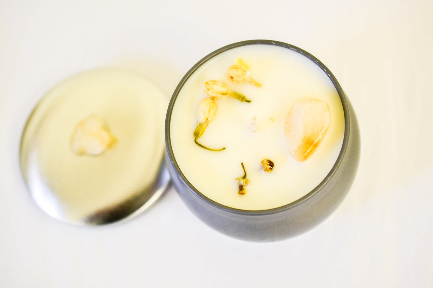 Container candle with visible herbs on a white background