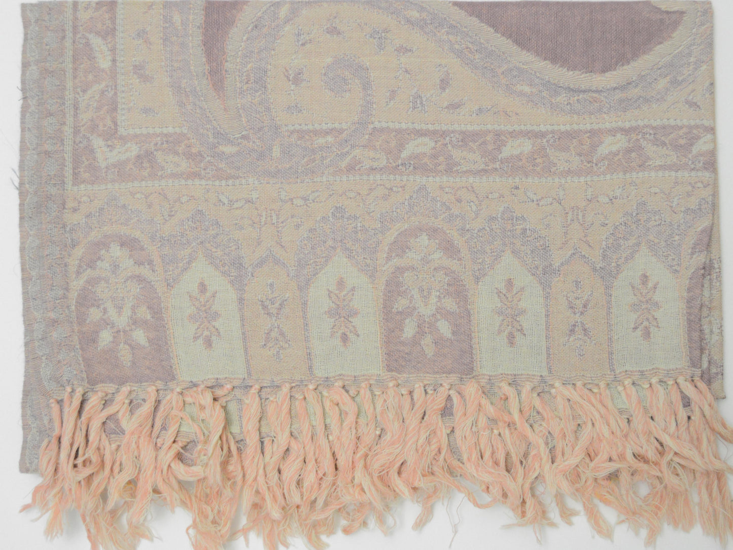 Shawl with intricate patterns and fringes on a plain background