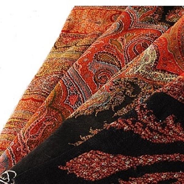 Close-up of a patterned shawl with intricate designs in red, black, and gold.
