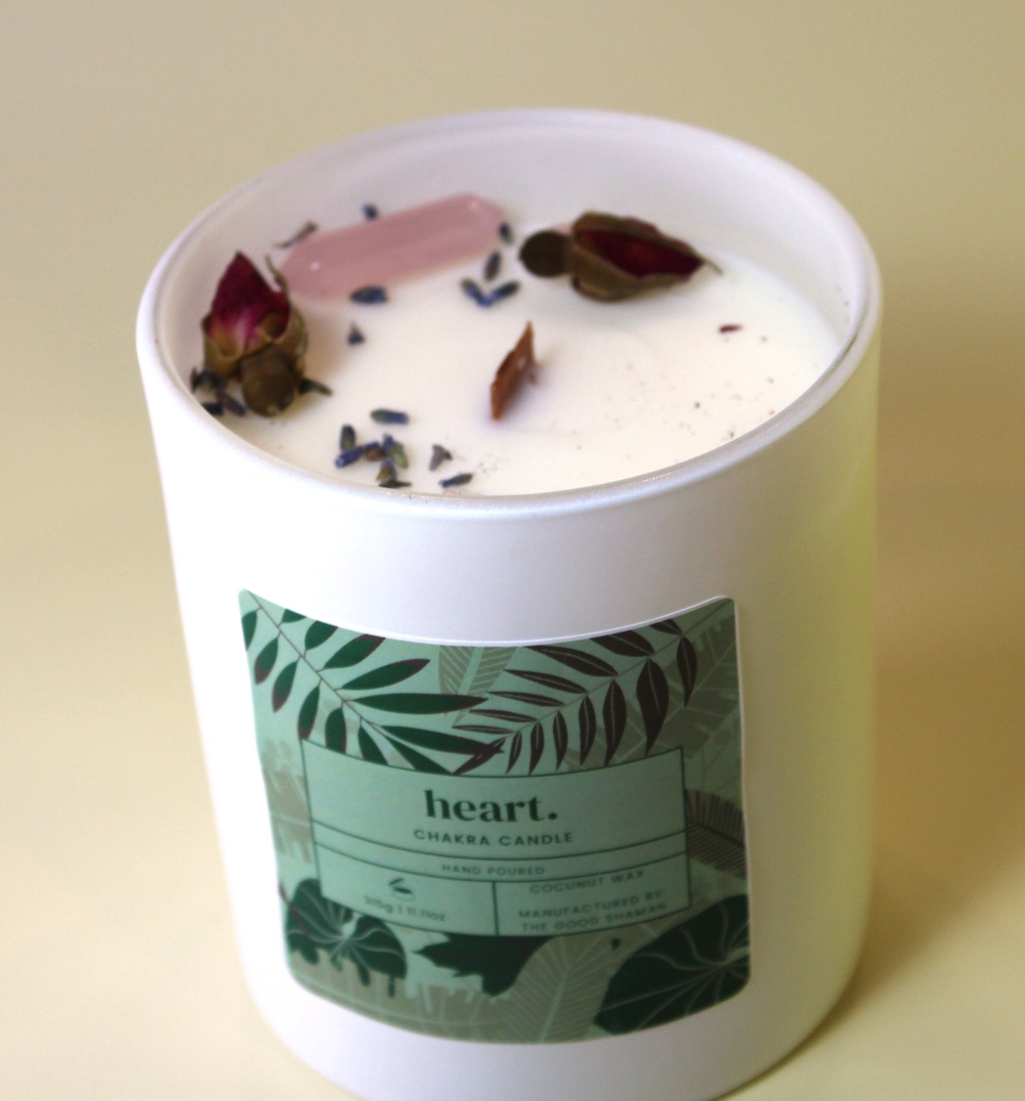 Candle with floral elements and a 'heart' label on a beige background