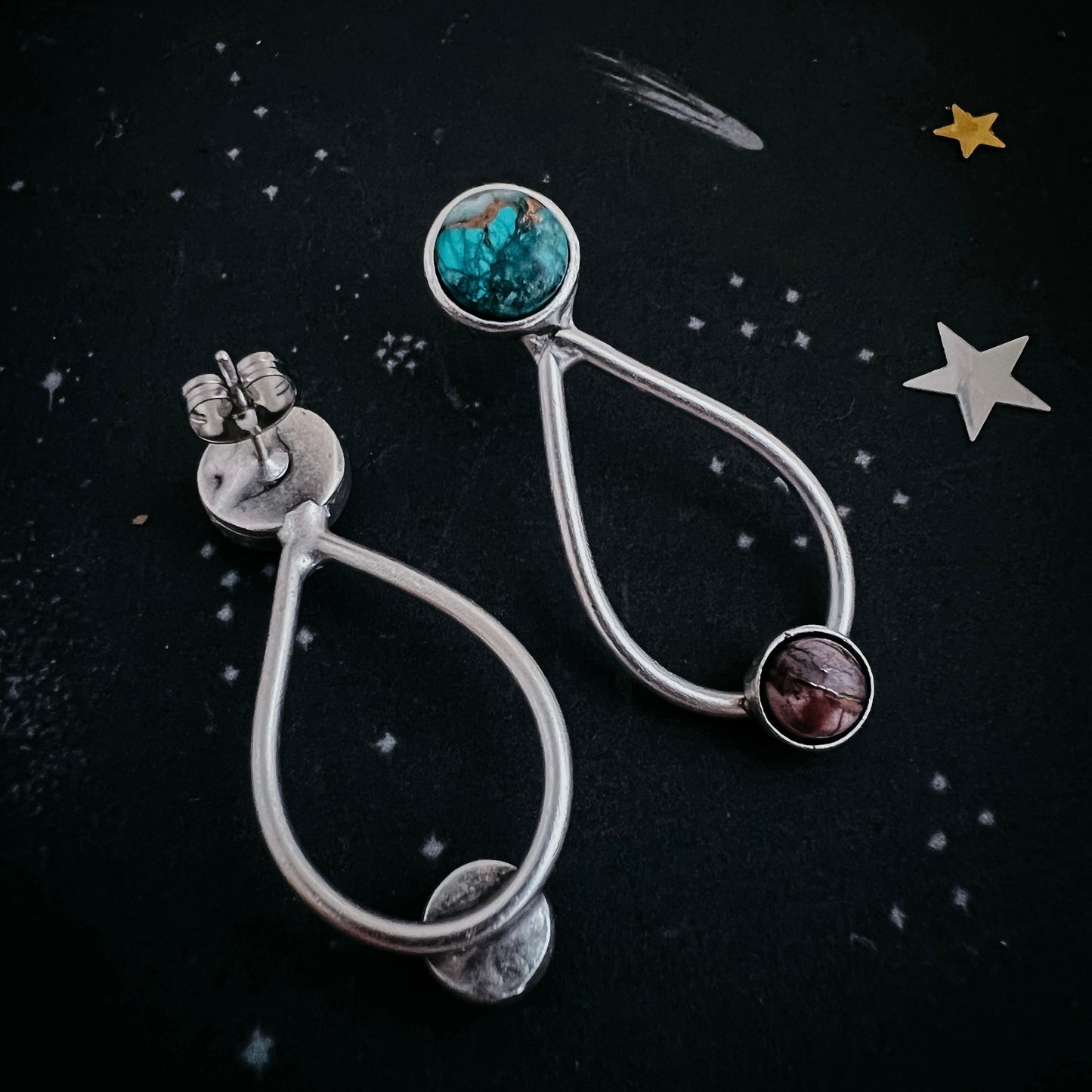 Silver earrings with gemstones on a dark background with star decorations