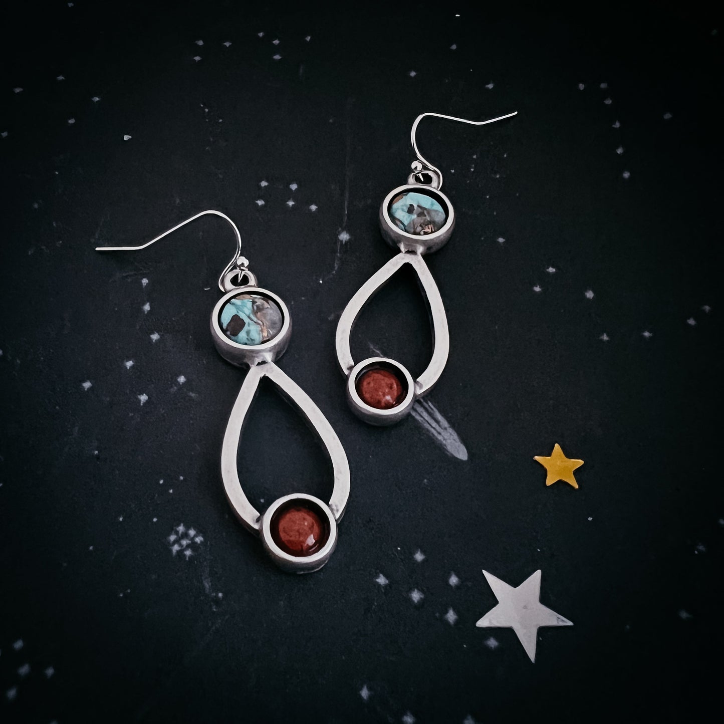 Silver earrings with gemstones on a dark background with star decorations