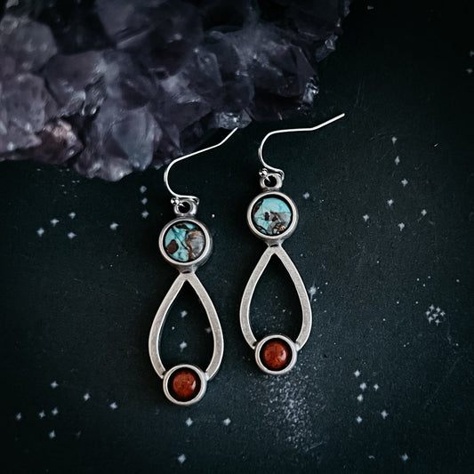 Silver earrings with gemstones on a dark textured background