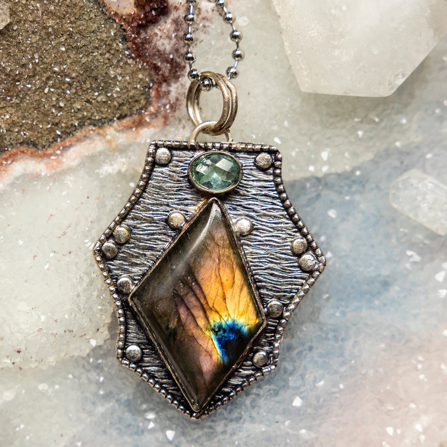 Necklace with a pendant featuring a colorful labradorite stone on a textured surface