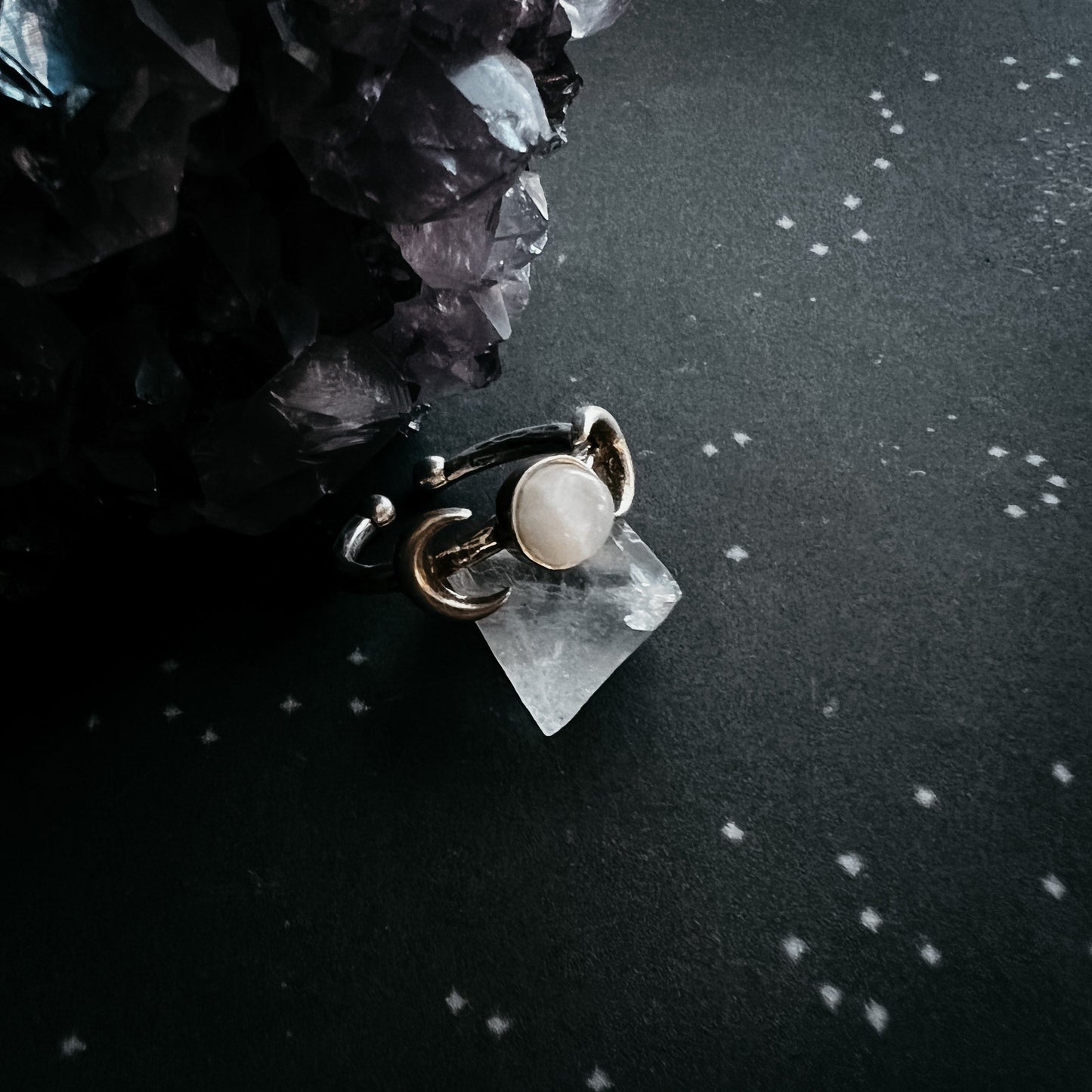 Ring with a central moonstone gemstone on a dark surface