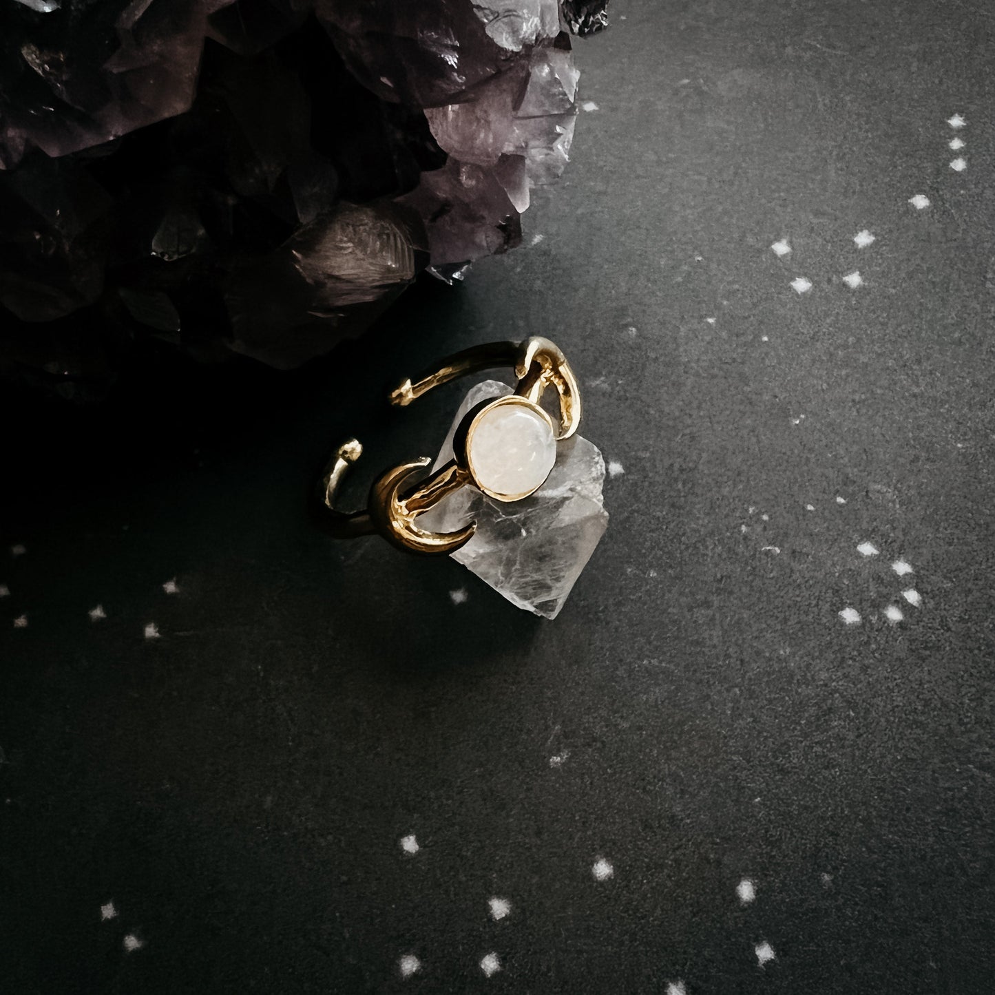 Gold ring with a moonstone on a dark surface with crystals