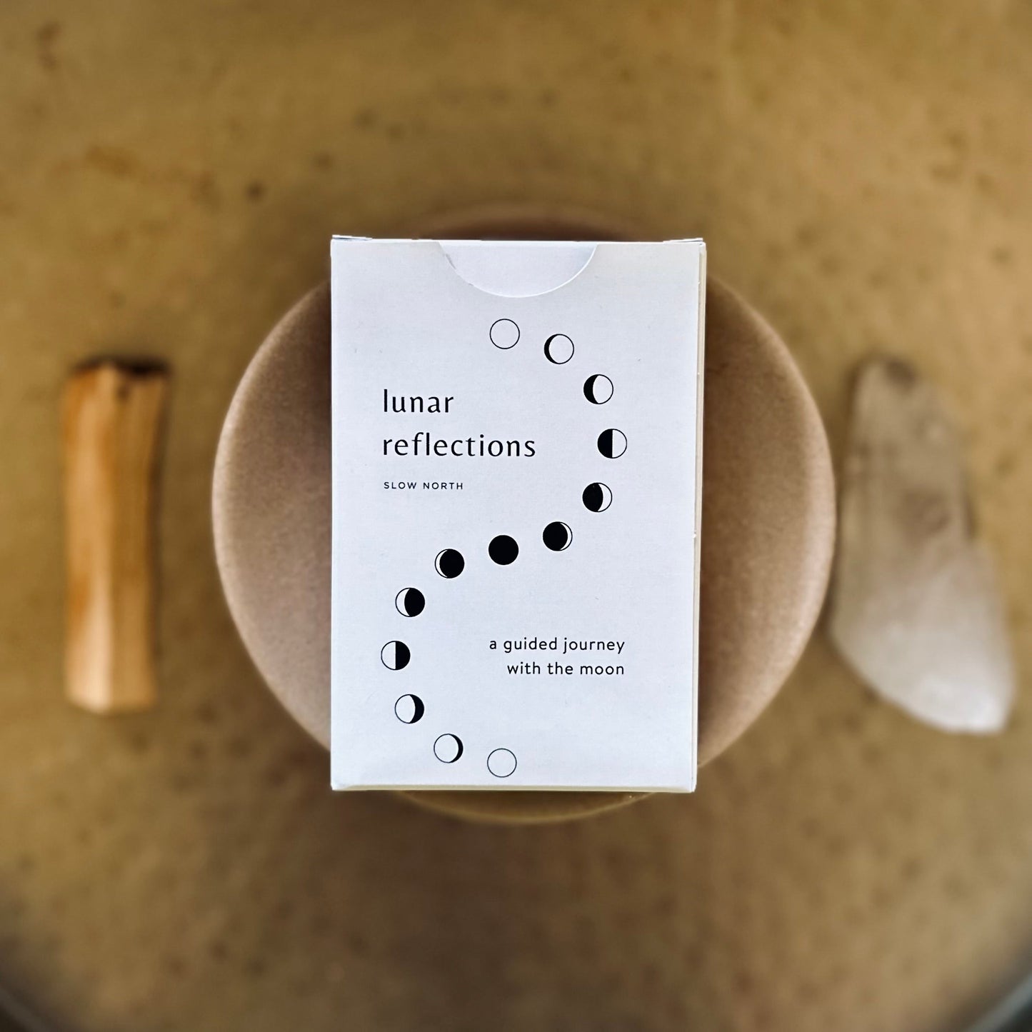 Box labeled 'lunar reflections' on a textured surface with natural elements.