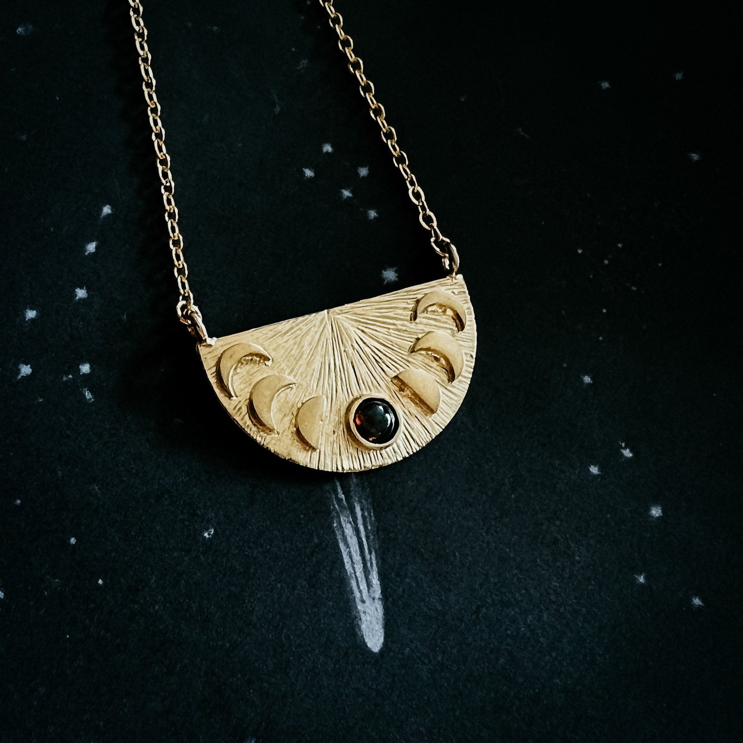 Gold necklace with a half-circle pendant on a black background