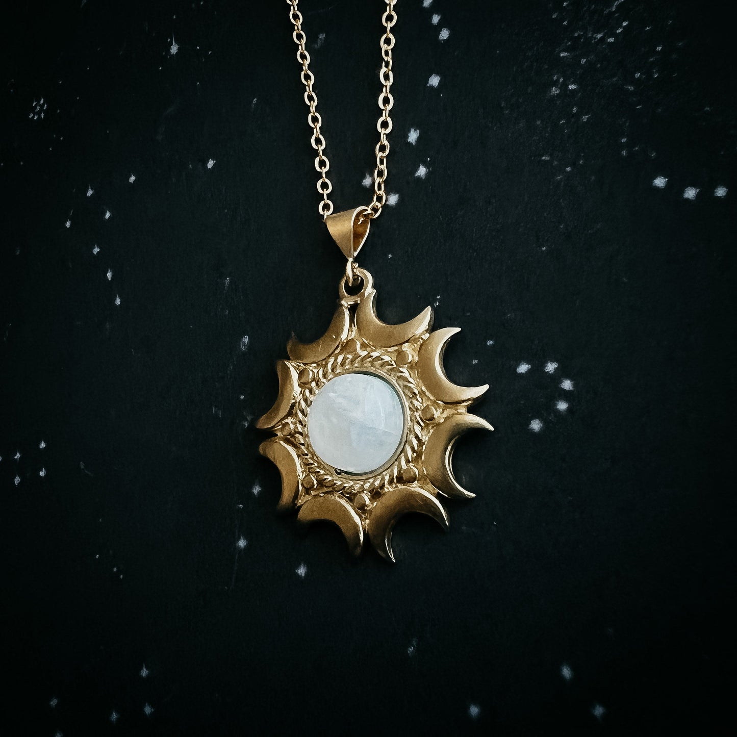 Gold pendant necklace with a moonstone on a dark background