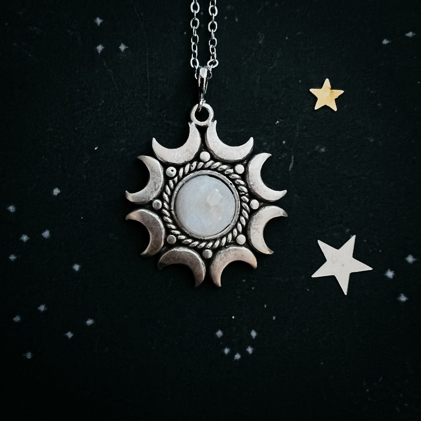 Moonstone pendant necklace on a black background with stars.