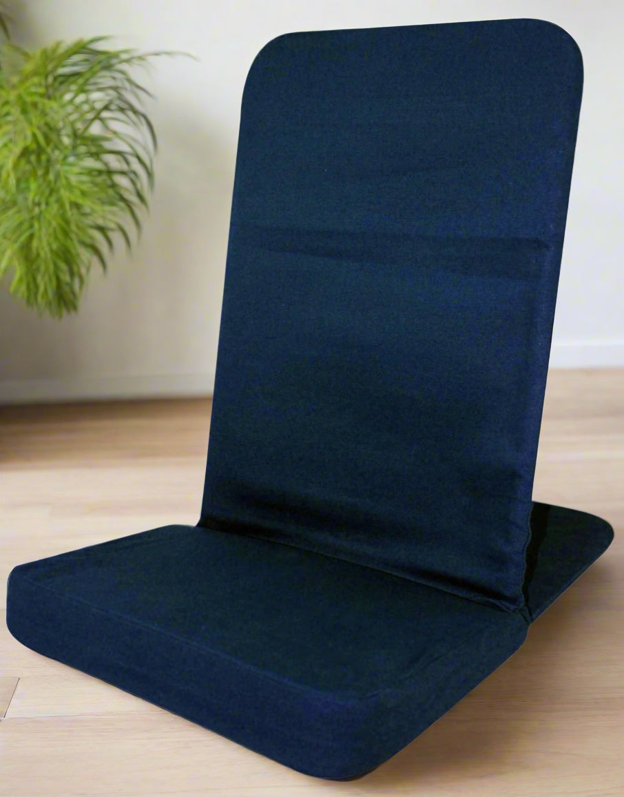 Navy blue folding meditation chair on a wooden floor with a plant in the background