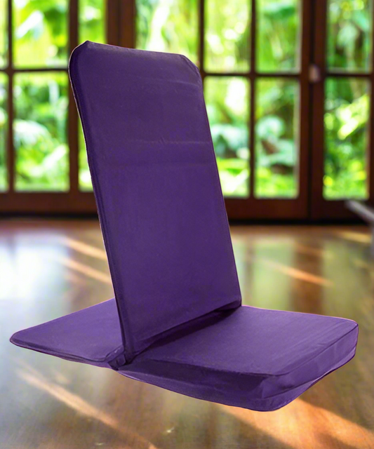 Purple folding meditation chair on a wooden floor with a blurred green outdoor background