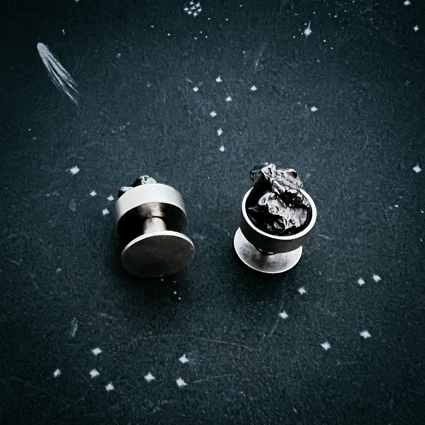 Two meteorite cufflinks on a textured dark surface