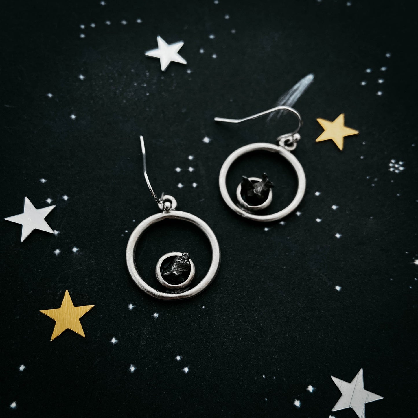 Silver earrings with star accents on a black background with star decorations