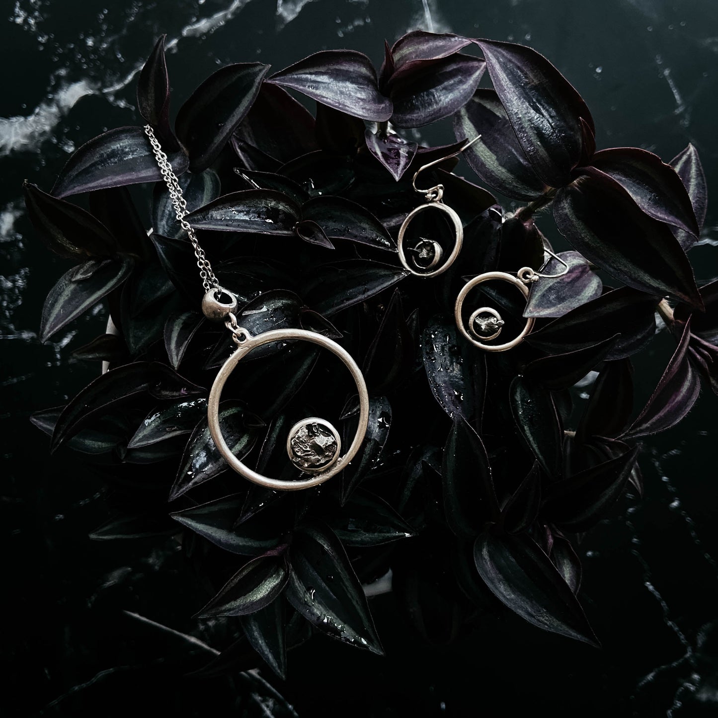 Circular jewelry set on dark leaves