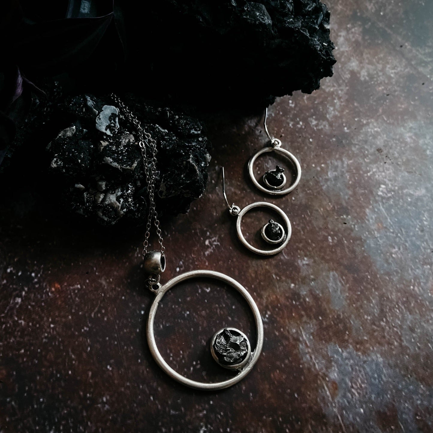 Pair of silver hoop earrings with central gemstone on a dark surface