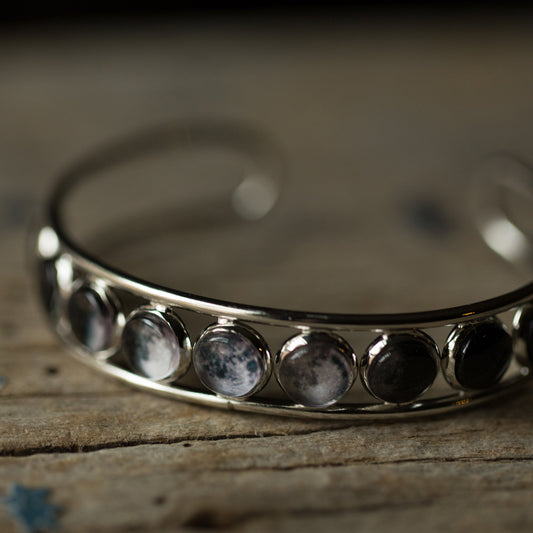 Silver bracelet with embedded stones on a wooden surface