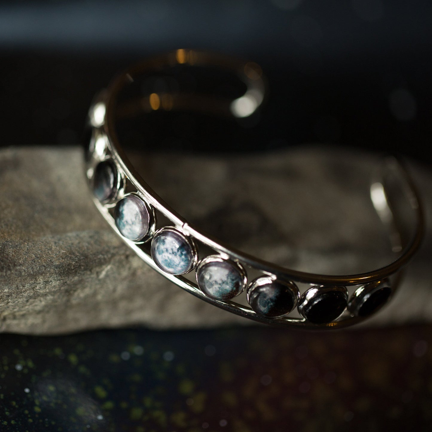 Silver bracelet with embedded stones on a dark background