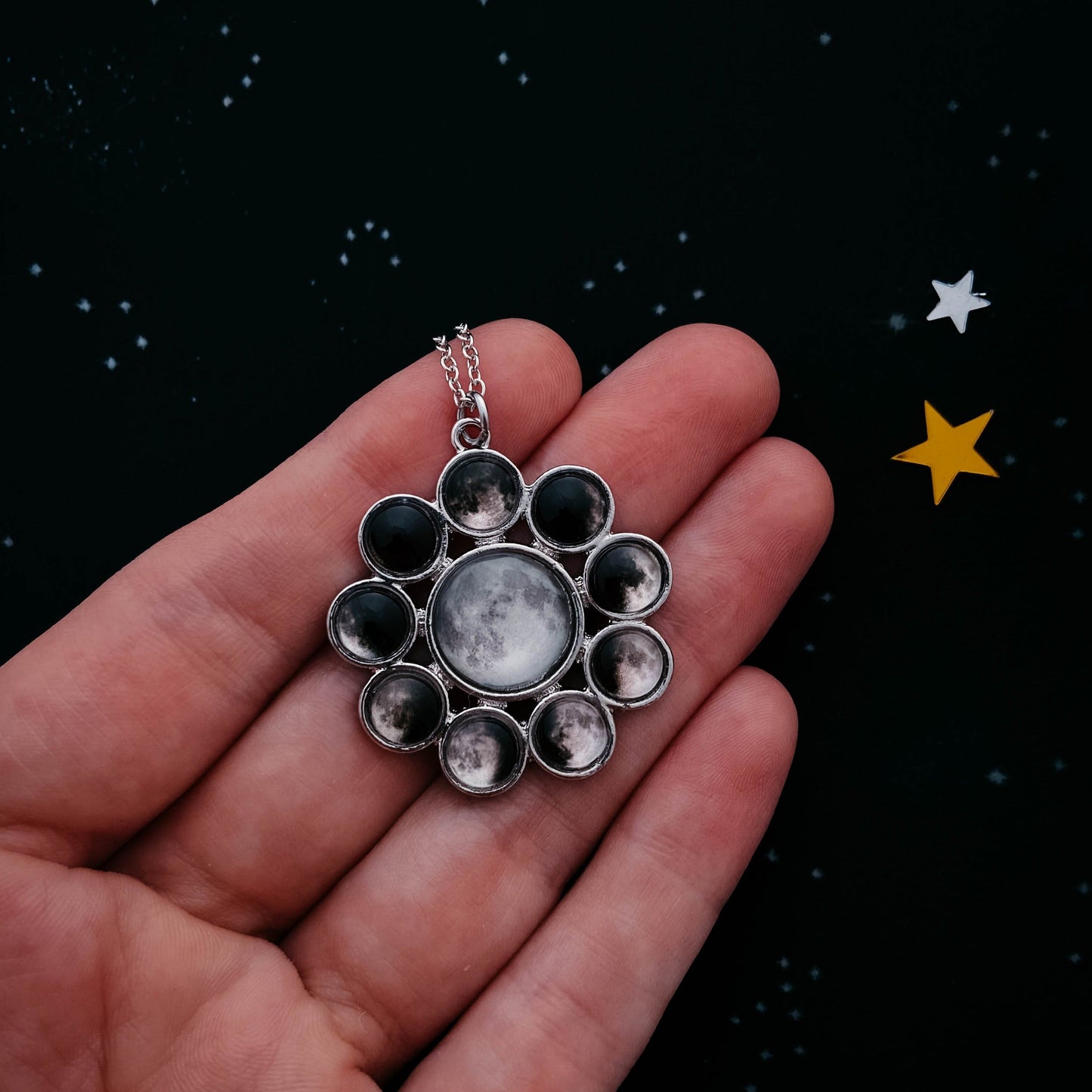 Silver necklace with a circular pendant featuring multiple smaller circles on a dark background with stars.