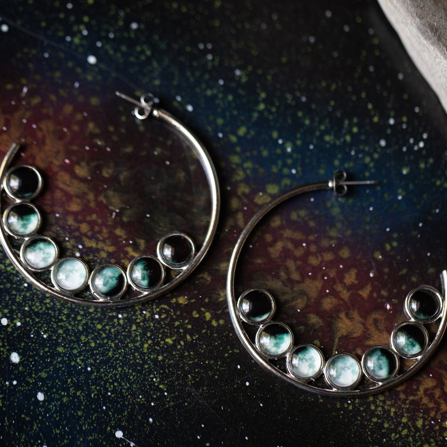 Hoop earrings with embedded stones on a dark, textured surface
