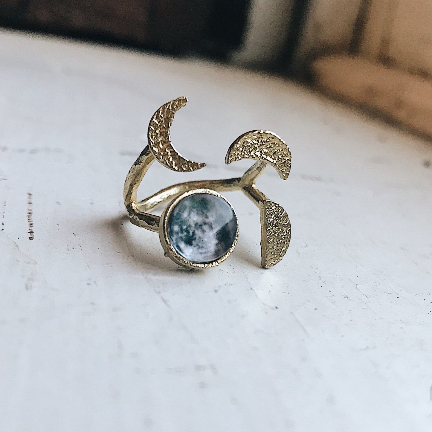 Gold tone ring with moon and star design on a textured surface