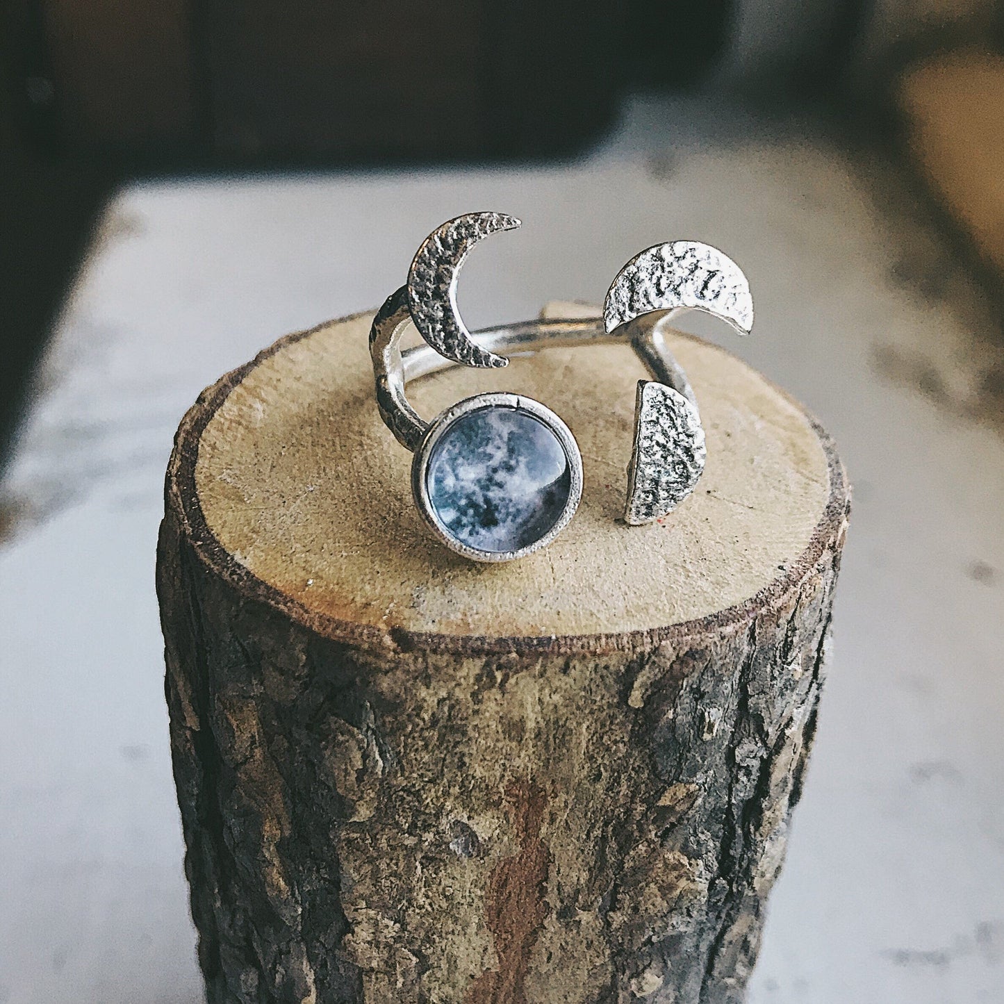 Silver tone ring with moon design on a wooden block
