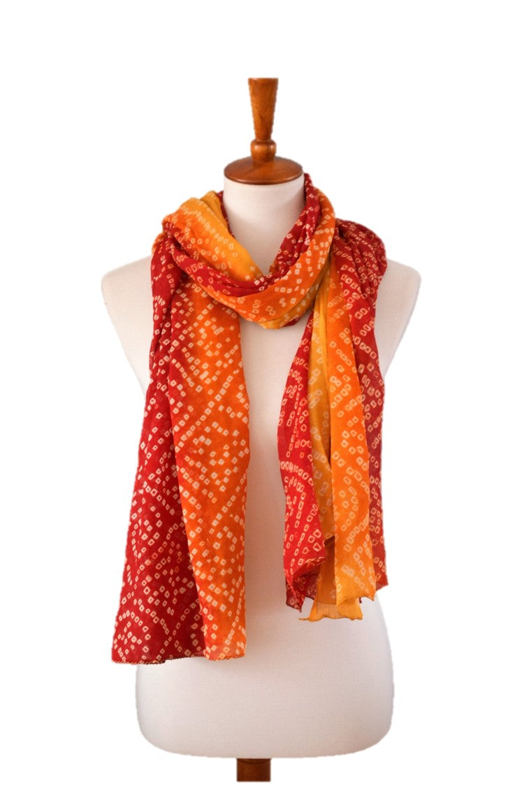 Mannequin wearing a colorful silk scarf with red, orange, and yellow patterns on a white background