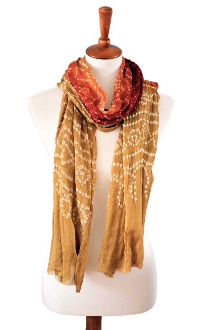 Mannequin wearing a mustard yellow silk scarf with a red patterned top on a white background