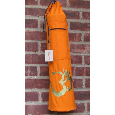 Orange yoga mat bag with a gold Om symbol against a brick wall.